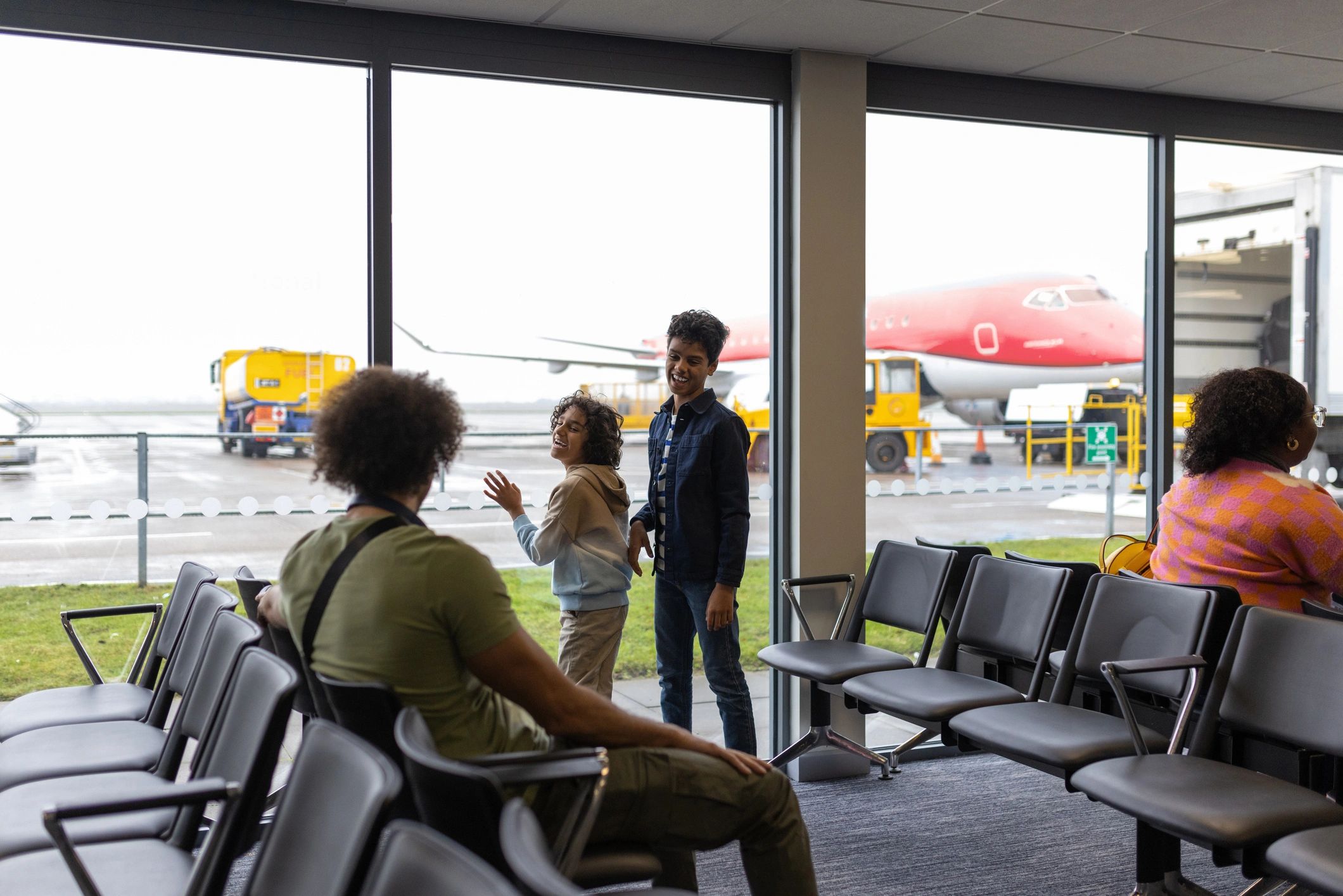 Family travelers looking out at an airplane from the airport lounge