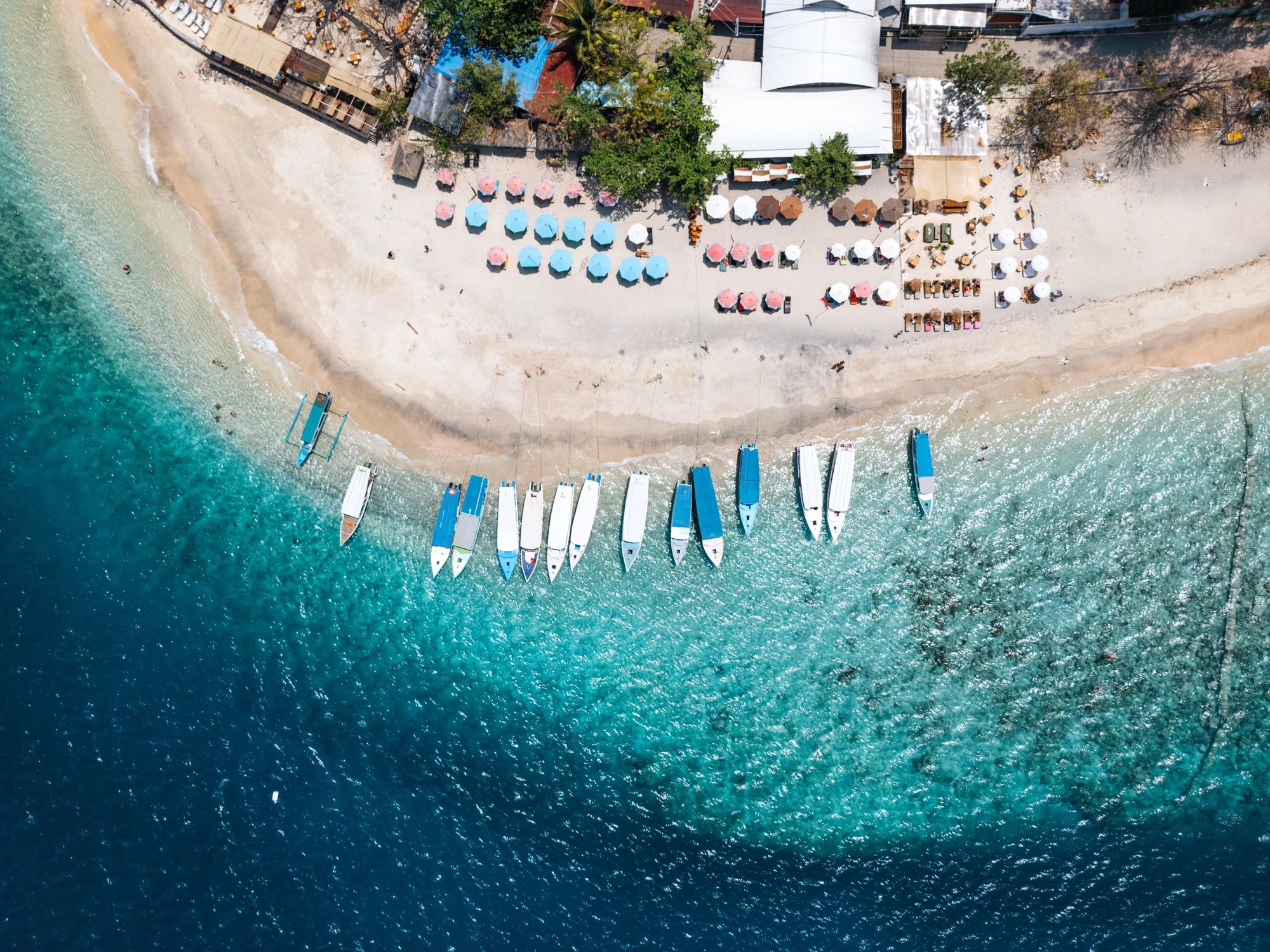 Tropical beach with boats and umbrellas